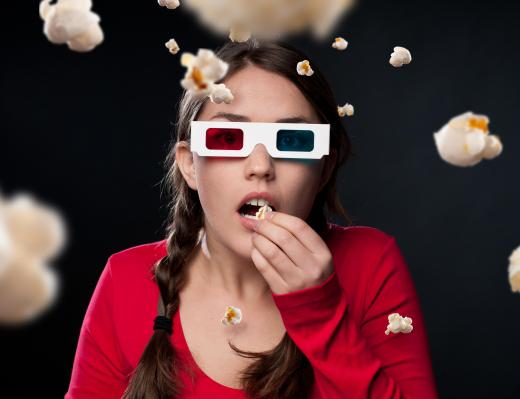 A girl wearing passive 3d glasses while watching a movie.